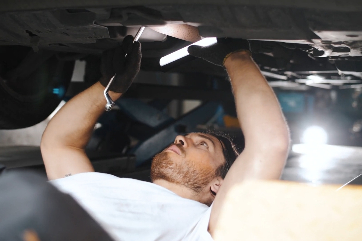 mladi automehaničar popravlja automobil
