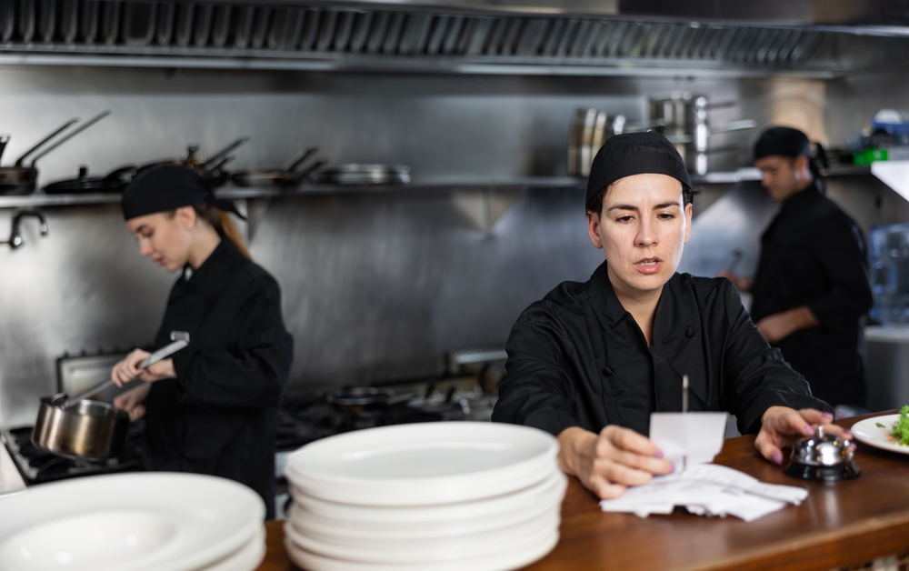 Osoblje u profesionalnoj kuhinji radi pod pritiskom dok proverava narudžbine i priprema jela